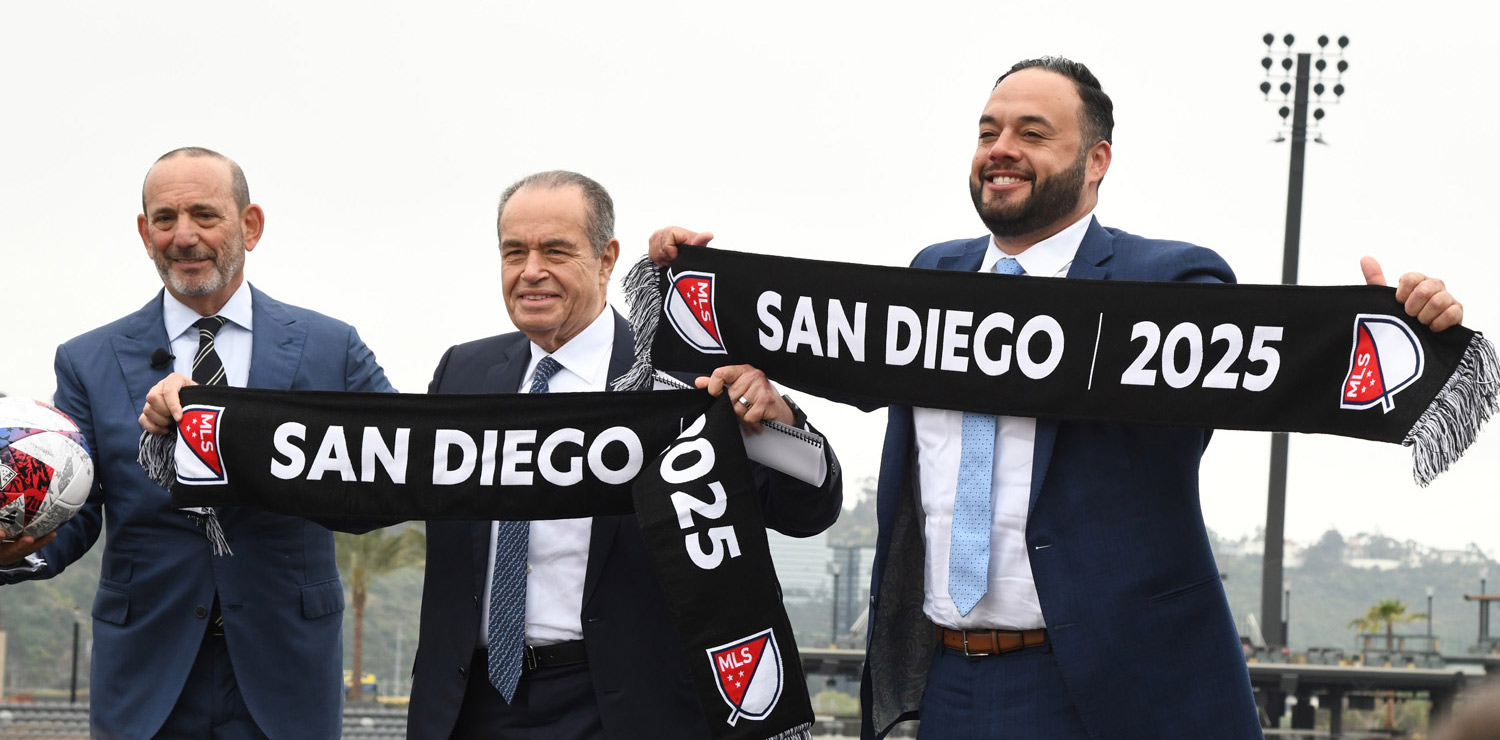 Three men dressed in suits with sashes that say 'MLS - San Diego 2025'